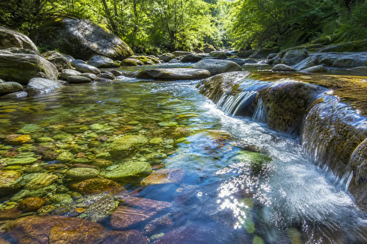 Pure mountain stream flowing over mineral-rich colorful stones